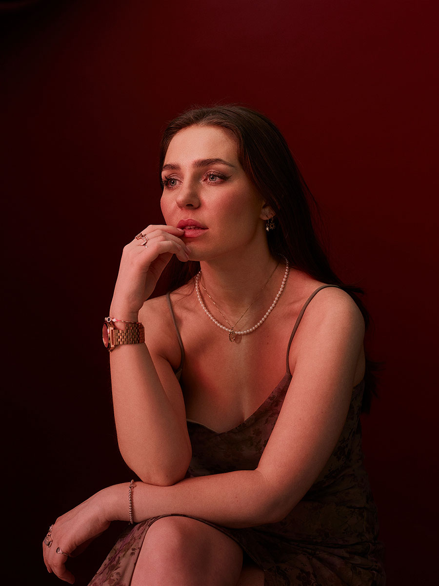 Portrait of actor, Bibi Lucille, looking off camera with her fingers resting on her lips.