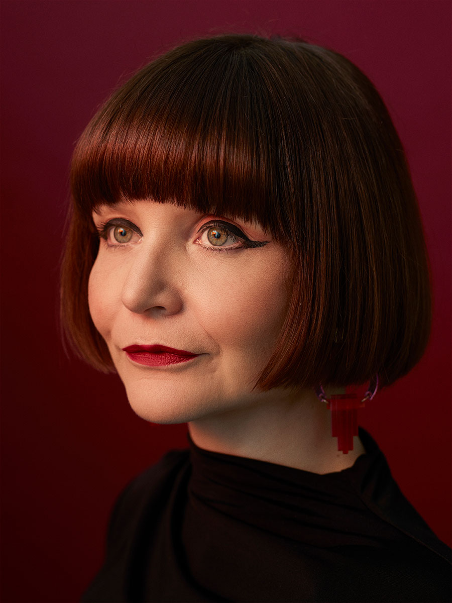 Portrait of creative director, Danielle Melia with red lighting tones and red background.