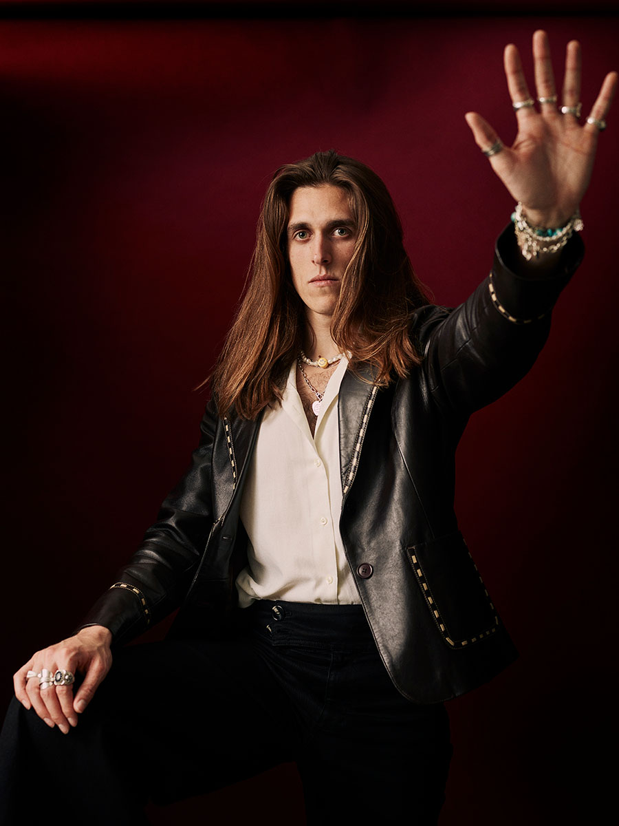 Photographic portrait of musician, Harry Morris, with one hand raised, palm towards the camera.